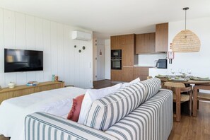 A modern room with a bed, a television, a kitchenette, and a dining area. - Wave 2.1 • Design and Conforto junto à Praia com AC (Vila Nova de Gaia)
