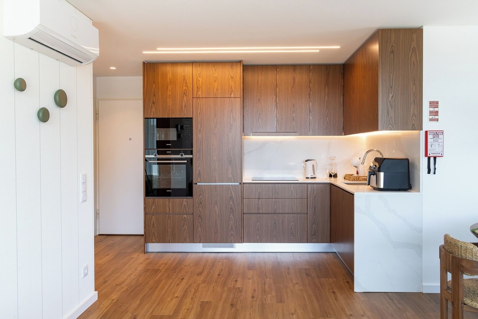 A modern kitchen with wooden cabinets, a built-in oven, and a countertop with a kettle and toaster.