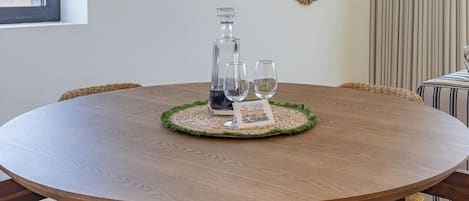 A round wooden dining table with a woven centerpiece, surrounded by wicker chairs.