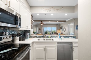 Una cocina moderna con armarios blancos, electrodomésticos de acero inoxidable y una isla grande con pileta.