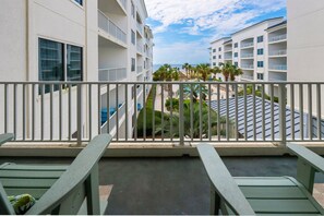 A balcony with a view of a resort area, including a pool and palm trees. - Beachfront 2BR @ Palm Beach Resort • Sleeps 6  • Stunning Views (Orange Beach)