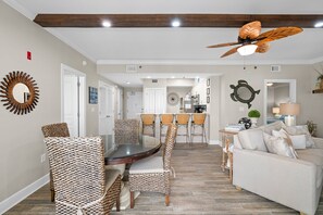 Ein modernes Wohnzimmer mit Essbereich, einer Küche im Hintergrund und einem Deckenventilator.