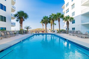 A swimming pool with lounge chairs and palm trees, surrounded by a white building with balconies. - Beachfront 2BR @ Palm Beach Resort • Sleeps 6  • Stunning Views (Orange Beach)