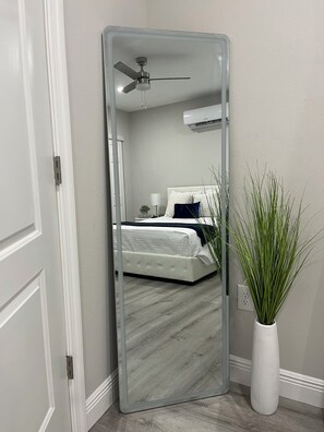 A room with a bed, a ceiling fan, and a large mirror reflecting the room. - Little Piece of Paradise (Tampa)
