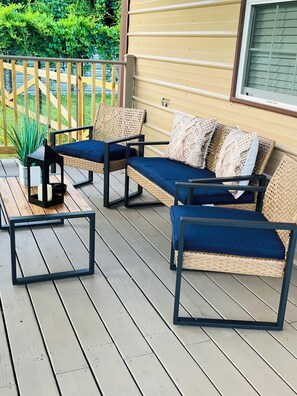 A wooden deck with a wicker sofa set, a small table, and a lantern. - Little Piece of Paradise (Tampa)