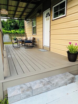 A wooden deck with outdoor furniture, a potted plant, and a sign indicating a porch area. - Little Piece of Paradise (Tampa)