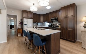Une cuisine moderne dotée d’un îlot central, de tabourets de bar, de meubles en bois et d’un four à micro-ondes.