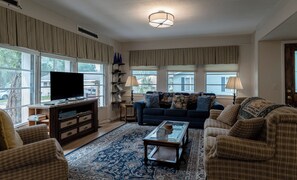 Ein Wohnzimmer mit Fernseher, Sofas, einem Couchtisch und einem gemusterten Teppich.