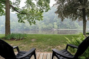 Eine Terrasse mit zwei Stühlen mit Blick auf einen von Bäumen umgebenen See.