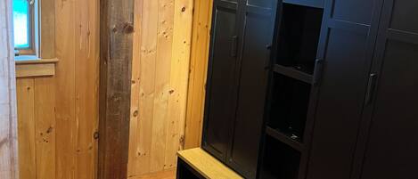 A wooden room with a bench, a window, and built-in black cabinets.