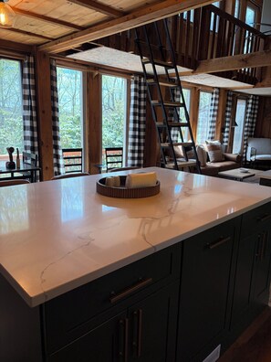 A kitchen with a large island, wooden cabinets, and a view of the outdoors. - Hillside retreat with modern finishes near Cooperstown and Oneonta (Oneonta)