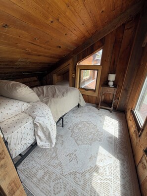 Ein Schlafzimmer mit Bett, Fenster und Nachttisch.