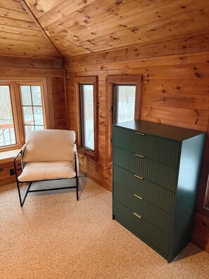 A room with wooden walls, a beige chair, and a green cabinet. - Hillside retreat with modern finishes near Cooperstown and Oneonta (Oneonta)