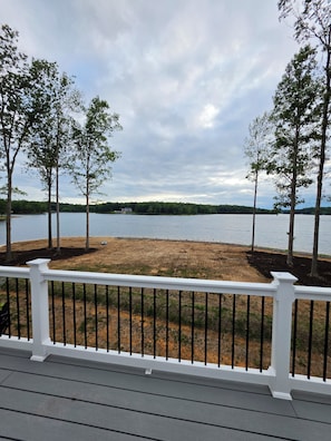 Una terrazza con ringhiera che si affaccia su un lago, circondata da alberi.