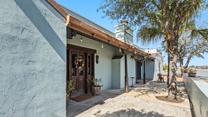 A building with a light blue exterior, a wooden door, and a porch area with string lights. - Hacienda Verde Spanish Style Home in the RGV (Weslaco)