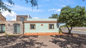 A small building with a brick facade, a green door, and a window with a sun-shaped decoration. - Hacienda Verde Spanish Style Home in the RGV (Weslaco)
