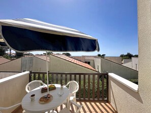 Un balcone con tavolo, sedie e un ombrellone grande.