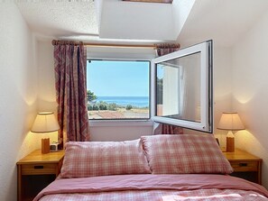 A bedroom with a bed, two bedside lamps, a window with a view of the sea, and a curtain. - Port Saint-Jacques by Interhome (La Bernerie-en Retz)