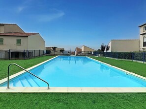 A rectangular swimming pool with a metal ladder on one side, surrounded by green artificial grass and a blue fence. - Port Saint-Jacques by Interhome (La Bernerie-en Retz)