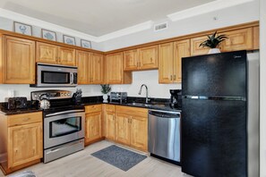 Una cucina moderna con mobili in legno, elettrodomestici in acciaio inossidabile e un frigorifero nero.