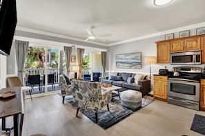 Ein modernes Wohnzimmer mit einer Couch, Sesseln, einem Couchtisch und Blick ins Freie.
