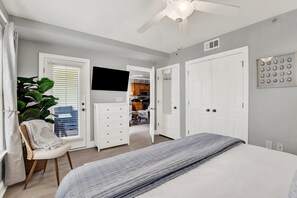 Un dormitorio con cama, una silla, televisor y armario.