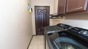 A laundry room with a washing machine, a door, and a towel rack.
