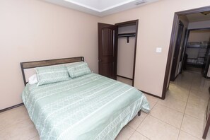 Un dormitorio con cama, armario y puerta que da a otra habitación.