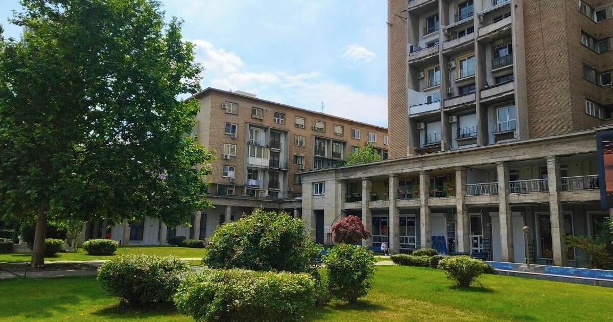 Ein Innenhof mit einem Gebäude, das mehrere Balkone und eine zentrale, begrünte Freifläche aufweist.