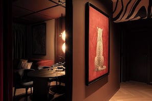 A dimly lit room with a round table, a sofa, and a framed artwork on the wall. - Velvet Noir Old Town (Bucharest)