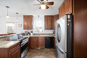 A kitchen with wooden cabinets, a stainless steel refrigerator, a dishwasher, and a ceiling fan. - Hudson House | 0.2 Miles to Red River (1726 Broadripple Drive) (Clarksville)