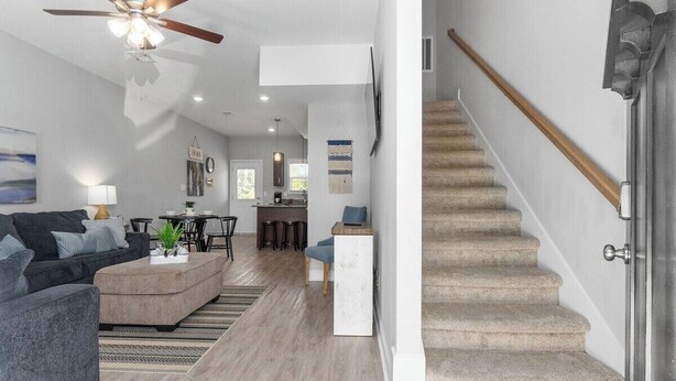 A modern living room with a sofa, coffee table, and a dining area with chairs. A staircase leads to the upper floor. - 19th Hole Haven in Sango (1625 Golf Club, #601) (Clarksville)