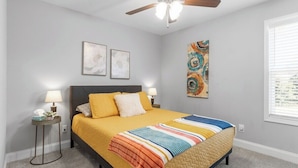 A bedroom with a bed, two bedside tables, a ceiling fan, and artwork on the walls. - 19th Hole Haven in Sango (1625 Golf Club, #601) (Clarksville)