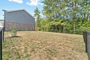 A backyard with a house, a small tree, and a fence.