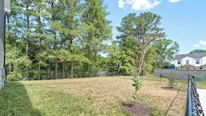 A fenced backyard with a grassy lawn, a small tree, and a house in the background. - 19th Hole Haven in Sango (1625 Golf Club, #601) (Clarksville)