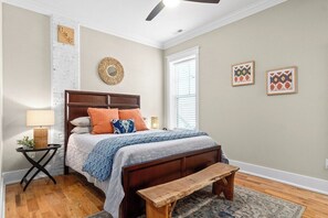 A bedroom with a wooden bed, a bench, a bedside table, and a window with blinds. - Todd's Place in Downtown (638 Madison St, #5) (Clarksville)