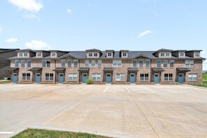 A multi-story building with a parking lot in front. - Peachers Place Townhomes (1000 Henry Place Blvd, #808) | Close to Ft. Campbell (Clarksville)