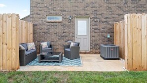 Una zona patio con mobili da esterno, un muro in mattoni e una porta.