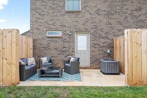 Eine Terrasse mit Gartenmöbeln, einer Ziegelwand und einer Tür.