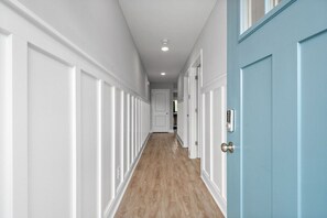 A hallway with white wainscoting, a blue door, and a wooden floor. - Peachers Place Townhomes (1000 Henry Place Blvd, #801) | Close to Ft. Campbell (Clarksville)