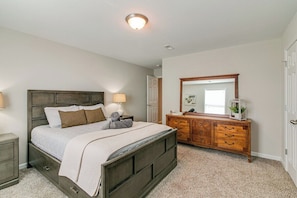 Une chambre à coucher avec un lit, des lampes de chevet, une commode, un miroir et une porte.