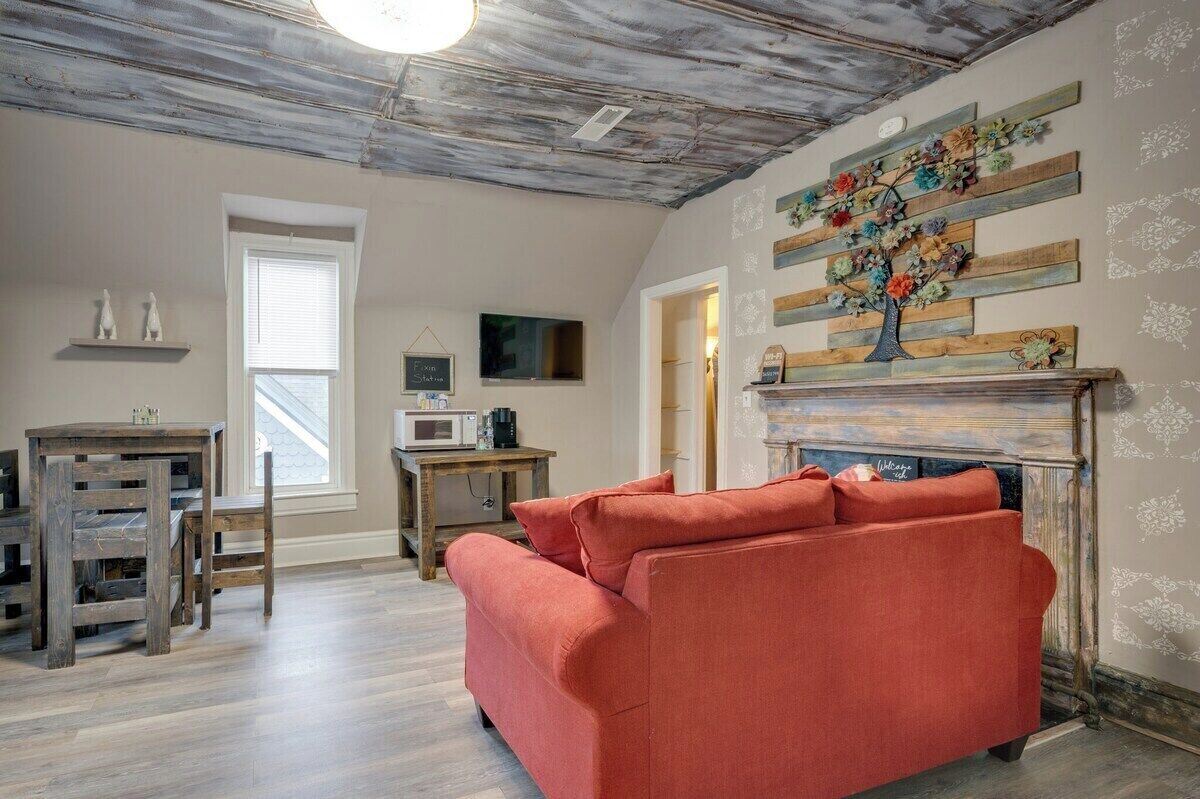 A living room with a red sofa, wooden table, and a fireplace with a floral decoration.