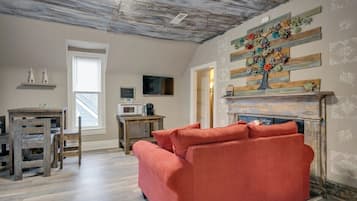 A living room with a red sofa, wooden table, and a fireplace with a floral decoration.
