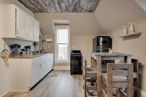 Une cuisine avec des meubles blancs, une cuisinière et une table en bois avec des chaises.