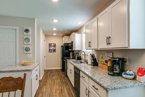 A kitchen with white cabinets, a granite countertop, and a wooden floor. - Franklin Haven by Johnathan (1010 Franklin, #B) (Clarksville)