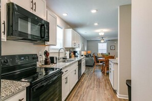 A modern kitchen with a black stove, white cabinets, and a microwave.