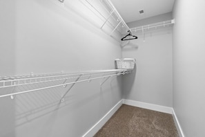 A laundry room with metal drying racks, a laundry basket, and a white wall. - Rebecca's Downtown Luxury Living (527 N 1st St) (Clarksville)