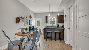 A modern kitchen with a central island, bar stools, and a dining area with a round table and chairs. - Tee Time Treasures in Sango (1625 Golf Club Ln, #602) (Clarksville)
