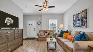 A modern living room with a flat-screen TV, a ceiling fan, a sofa, a coffee table, and a painting on the wall. - Tee Time Treasures in Sango (1625 Golf Club Ln, #602) (Clarksville)