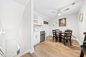 A modern kitchen with white cabinets, a stainless steel refrigerator, and a dining area with a wooden table and chairs. - Adam's Downtown Retreat with 2 Rooftop Patios (Clarksville)